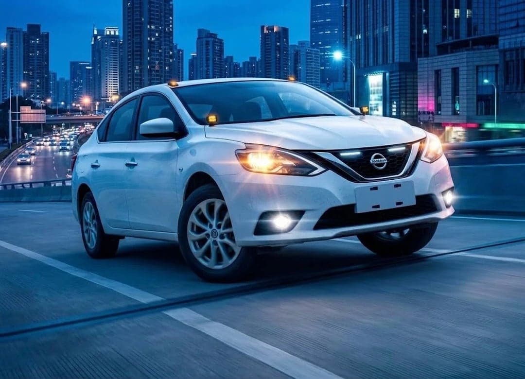 Nissan Sylphy Classic blanco en una avenida de la ciudad al anochecer